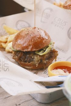 A delicious homemade cheeseburger with fries and condiments on a rustic surface, ideal for fast food lovers.
