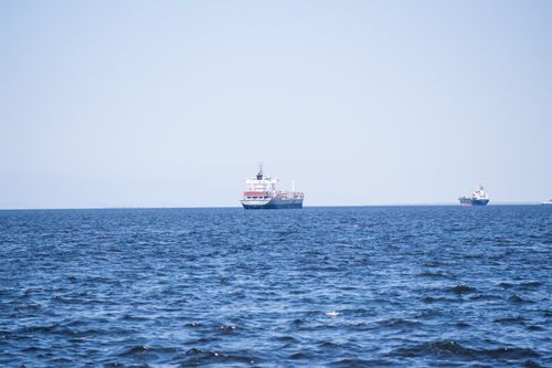 Free Cargo ships navigating the calm waters of the İzmir Gulf under clear skies, showcasing maritime transportation. Stock Photo
