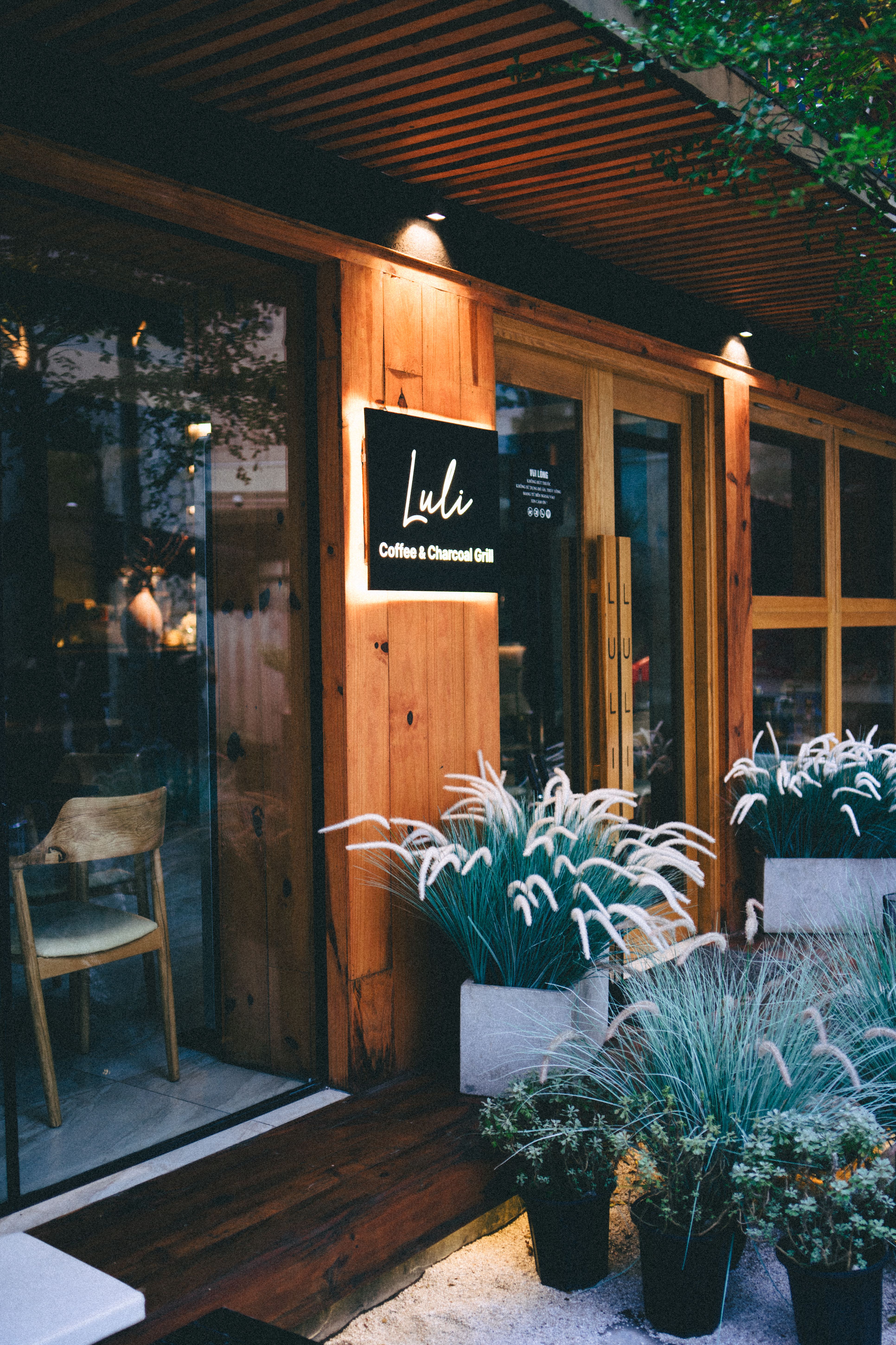 Cozy coffee shop entrance with wooden decor and lush plants.