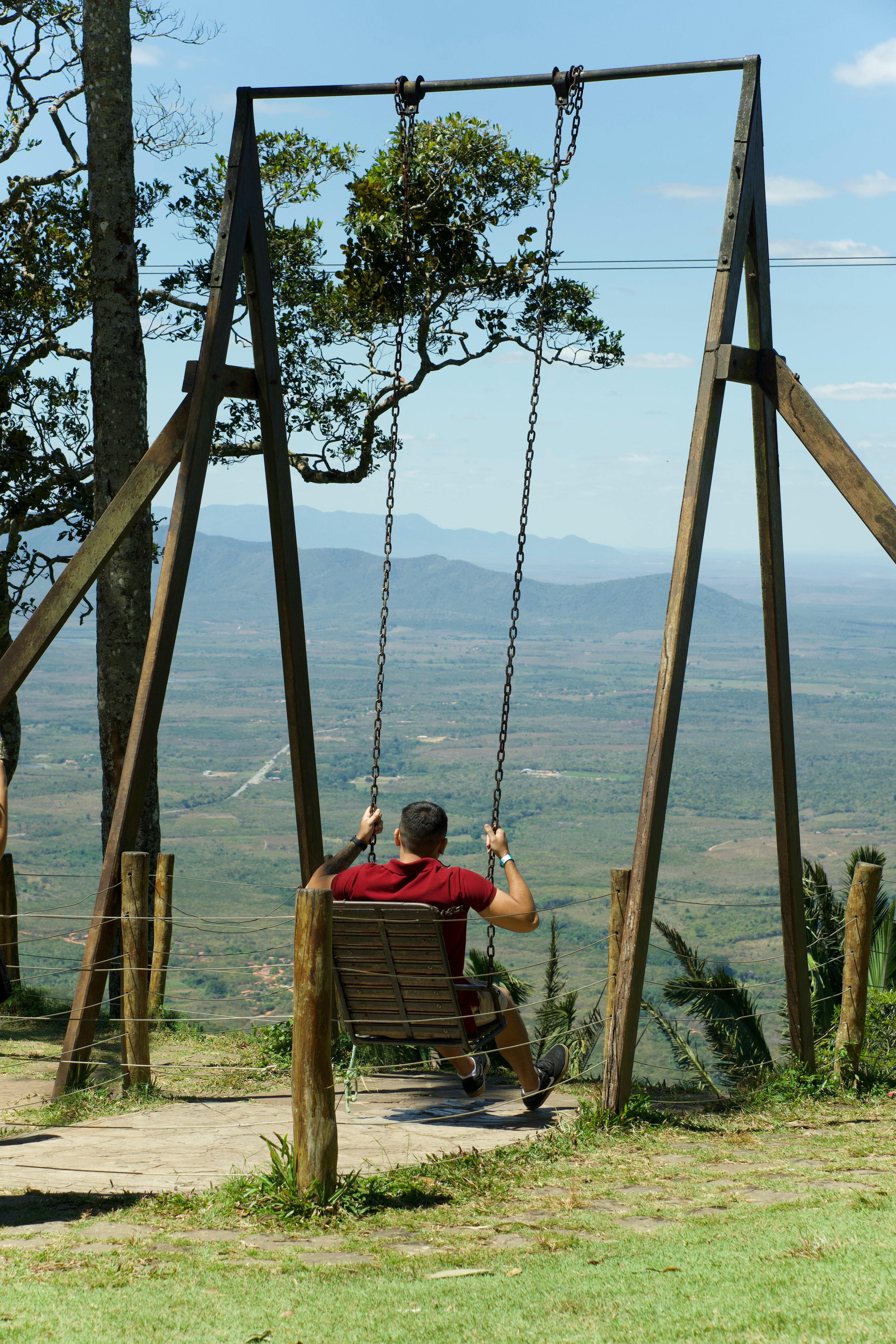 a man sitting on a swing in the middle of a field