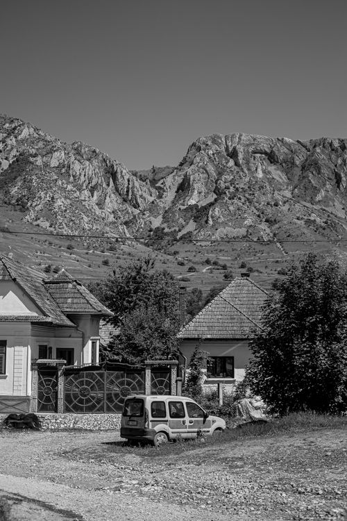Free Black and white photo of a quaint village nestled beneath rugged mountains, capturing rustic charm. Stock Photo