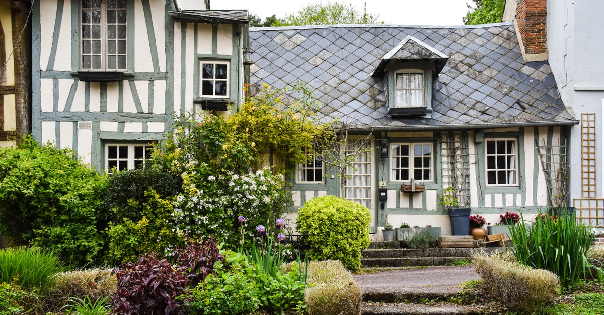 Quaint half-timbered house in Normandy surrounded by a vibrant garden.