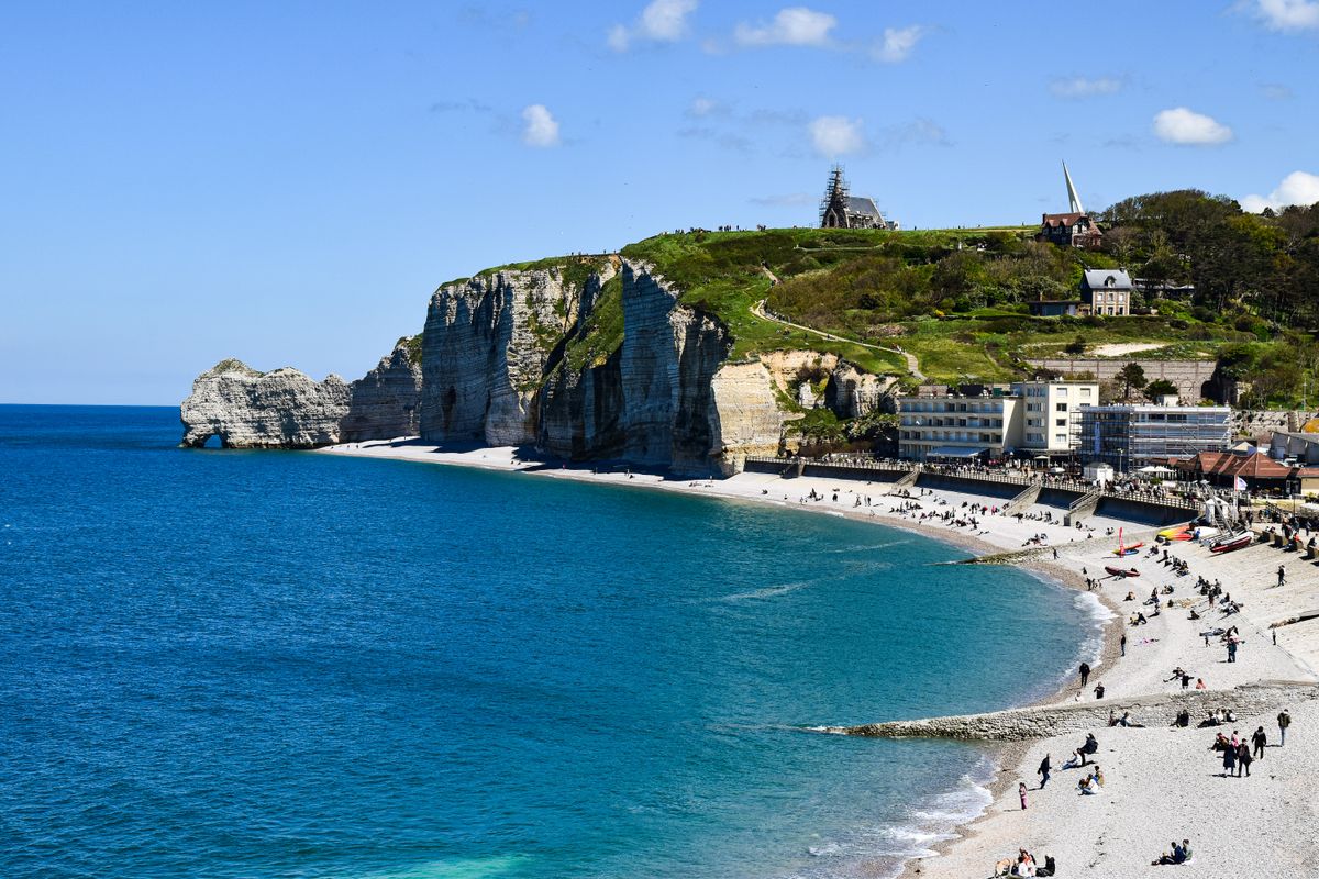 Plajă cu oameni și faleza alăturată, la Etretat