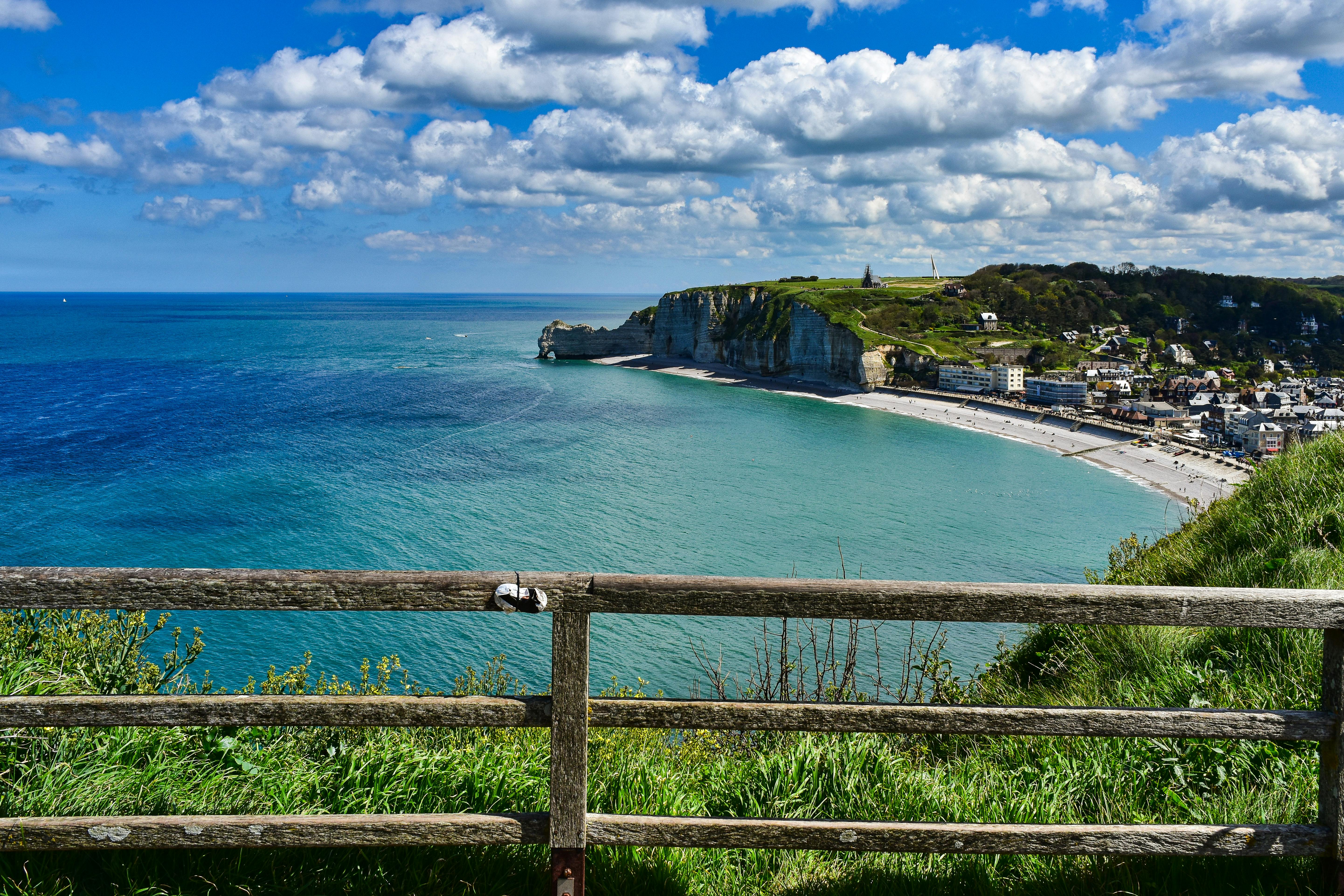 a view of the beach and cliffs from a wooden fence