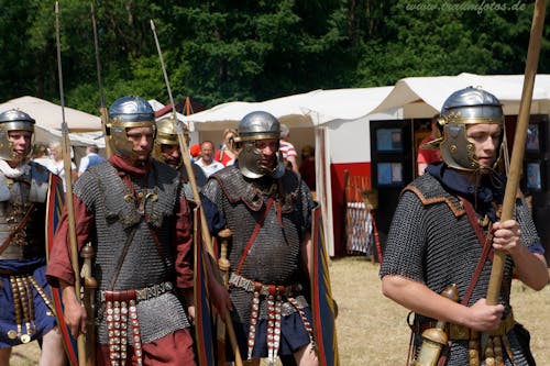 Military historical reconstruction male group in metal helmets and weapons in sunny warm day