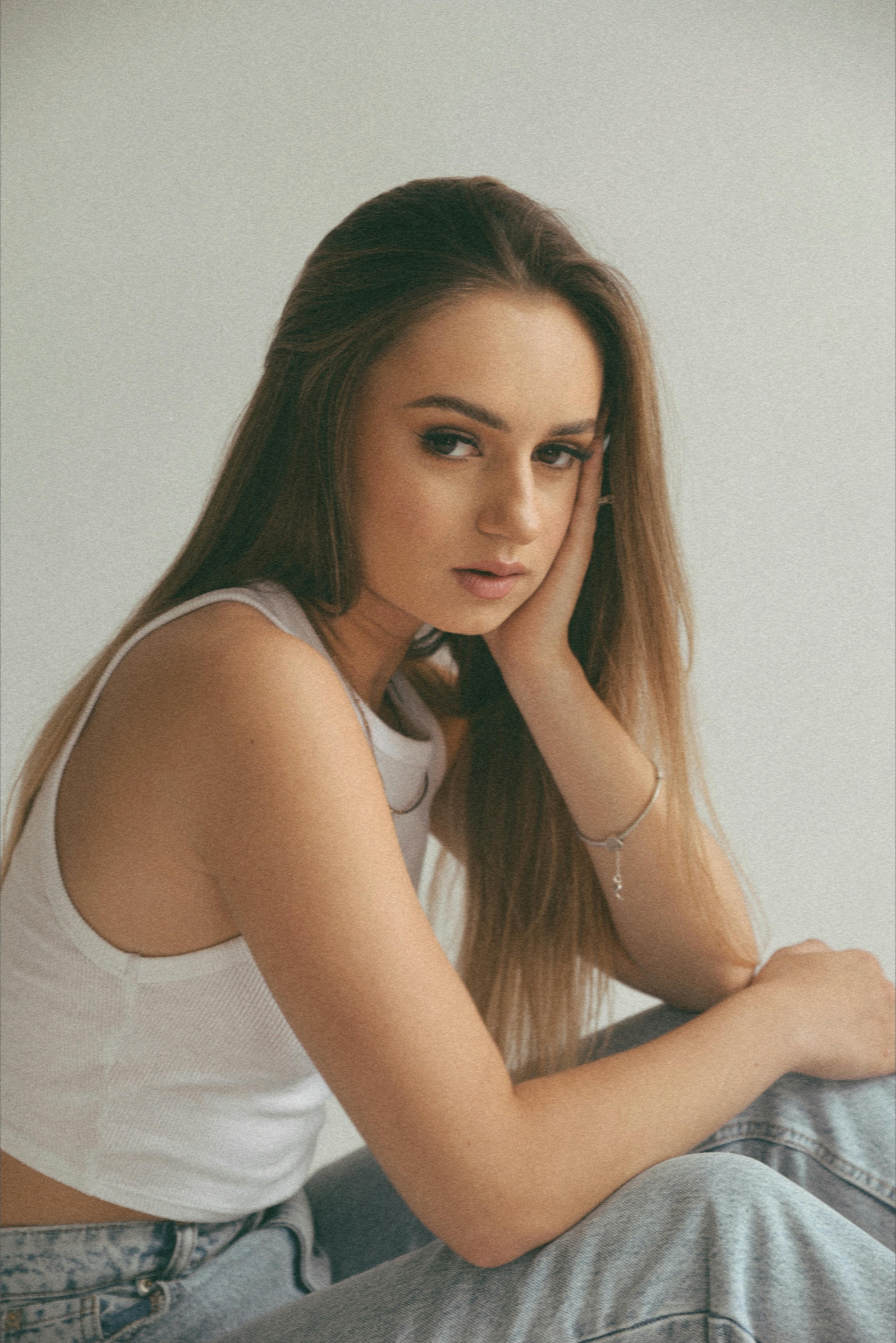 Portrait of a young woman in casual wear, looking pensive and relaxed indoors.