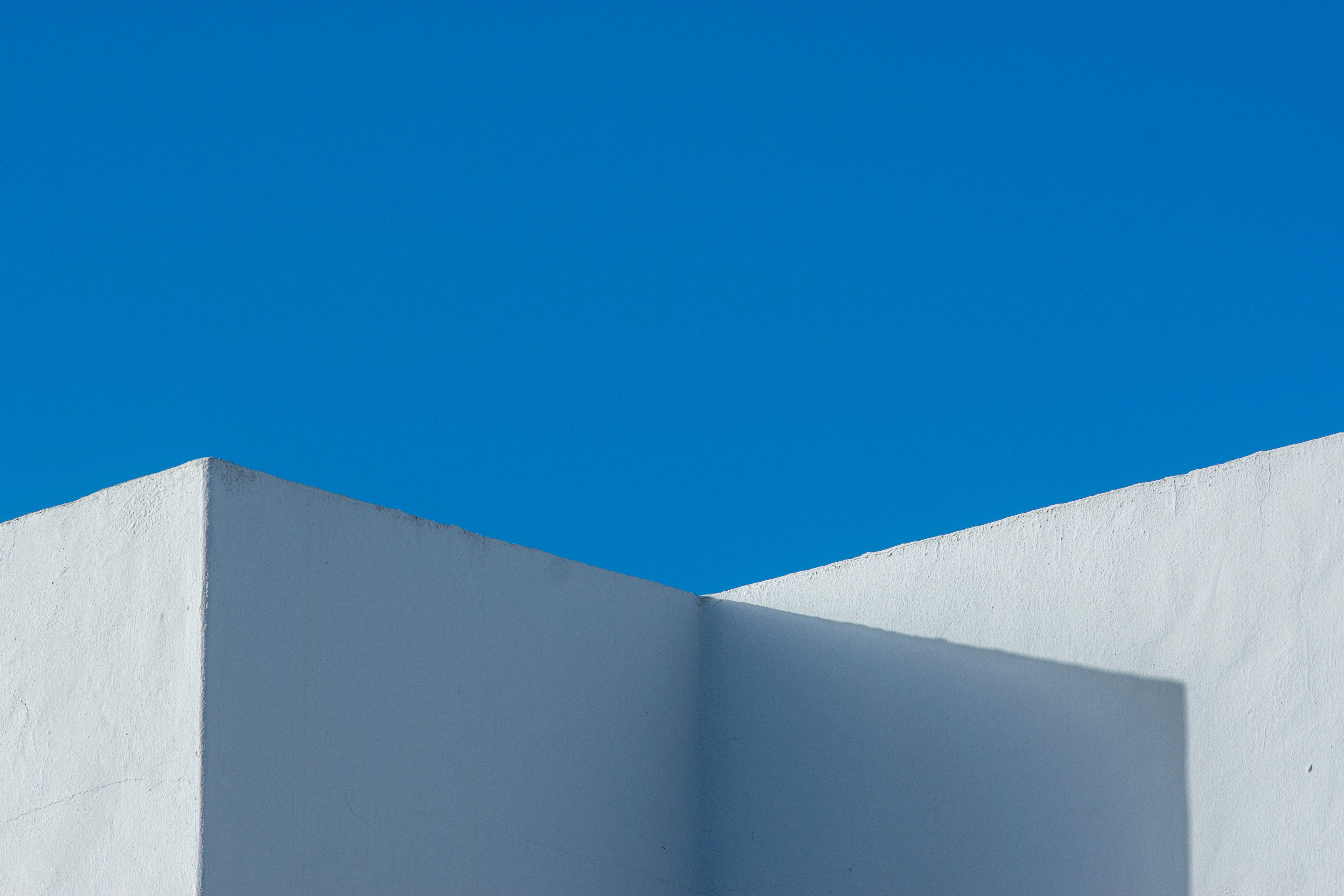 Minimalist design featuring a white wall against a vivid blue sky, showcasing modern architectural aesthetics.