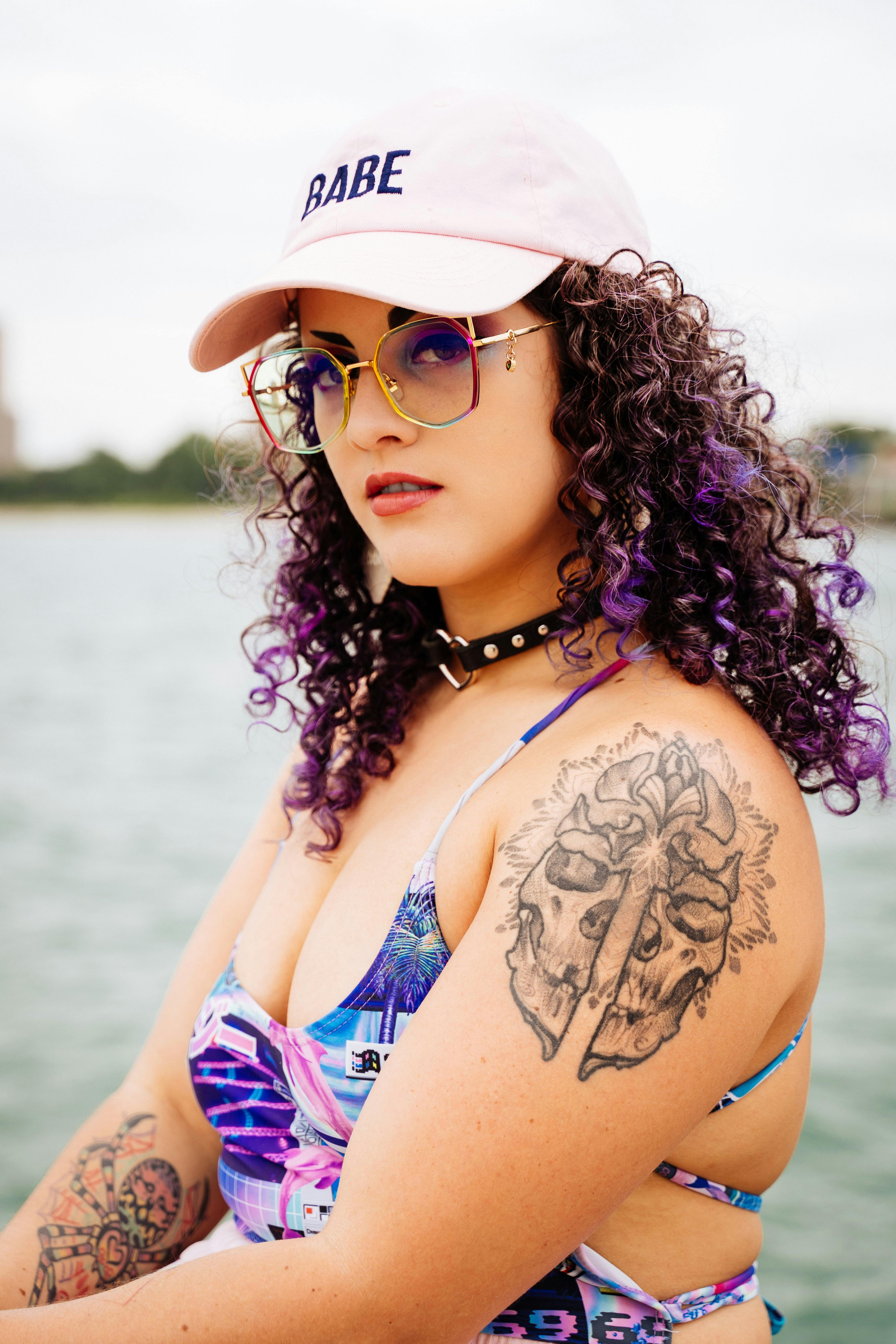 在芝加哥的湖边，一位留着卷发、有着时尚纹身的女子正摆出优雅的姿势