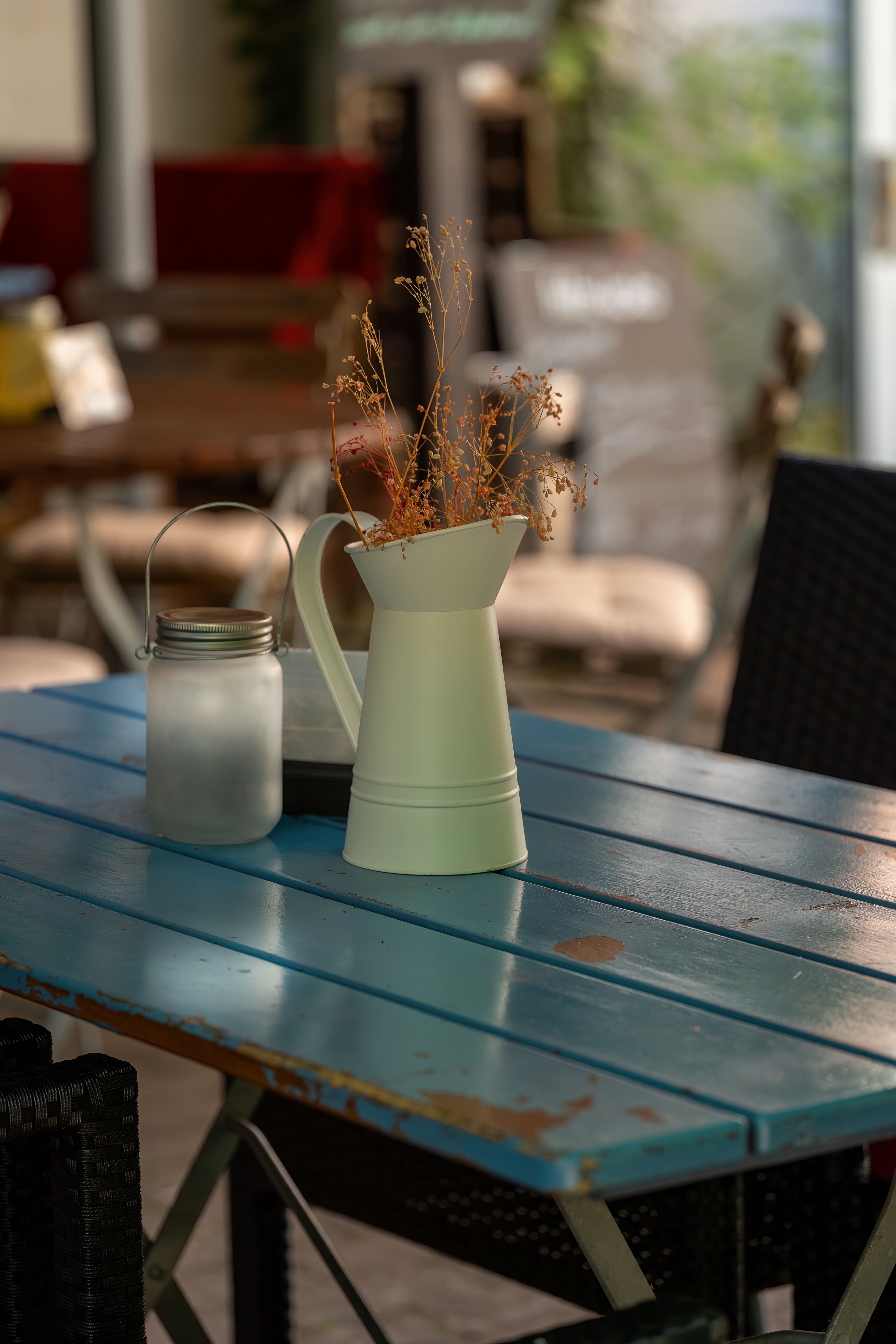 Fotomural Un detalle encantador de una mesa de café al aire libre con una jarra y decoración de linterna.