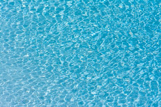 Texture and pattern of rippling turquoise water in a swimming pool with clear reflections.