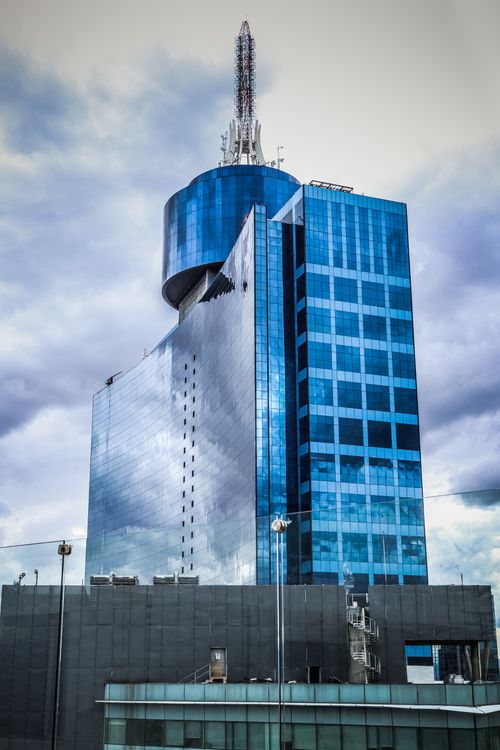 Free Modern blue glass skyscraper with a futuristic design in an urban environment. Stock Photo