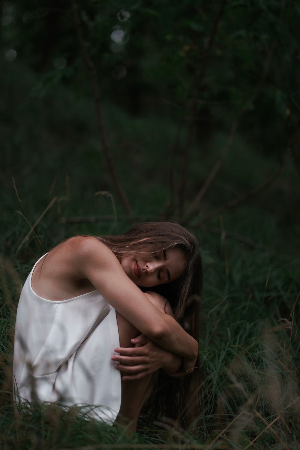 A woman in a white dress is sitting in the grass · Free Stock Photo
