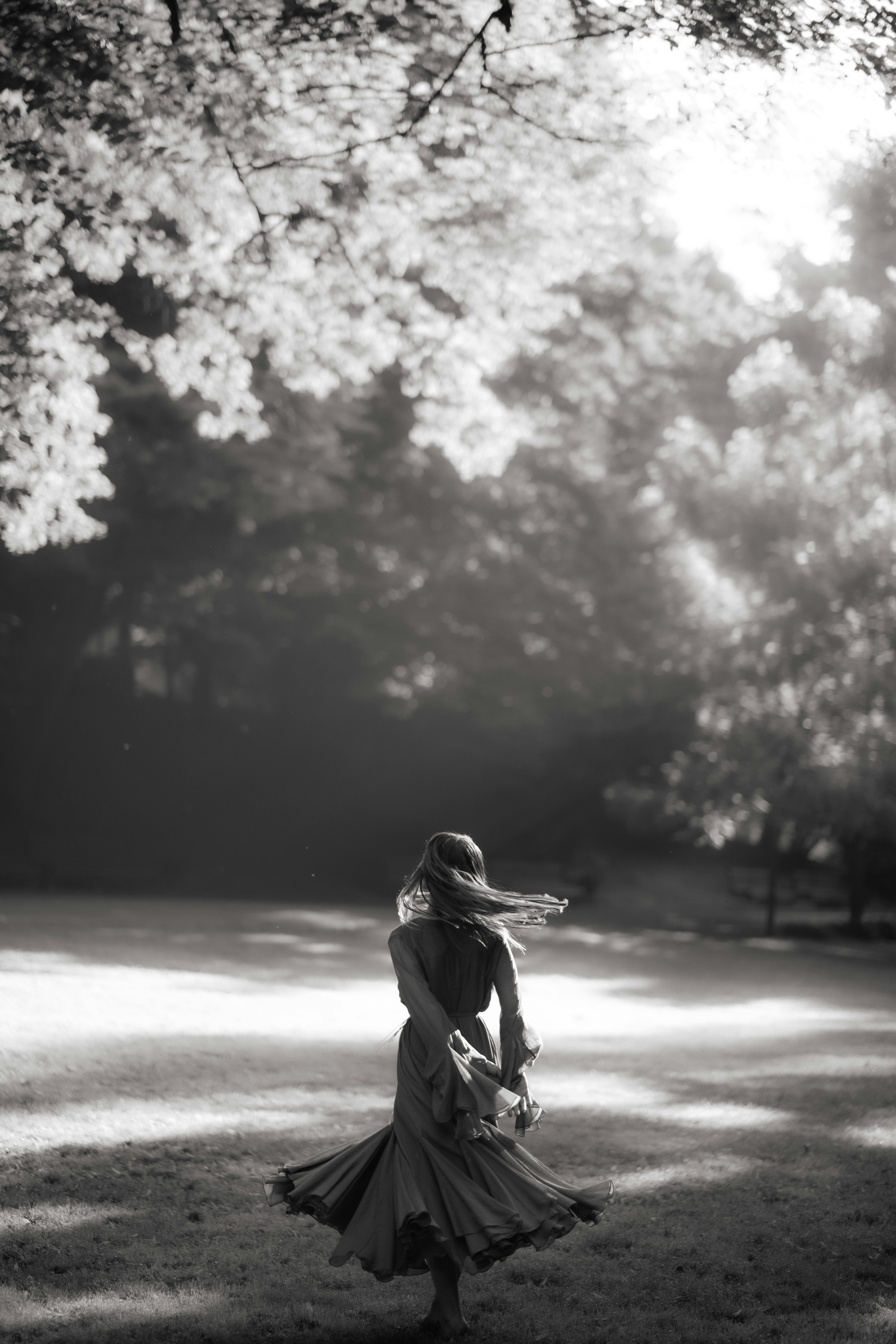 A captivating black and white portrait of a woman in a flowing dress twirling outdoors.