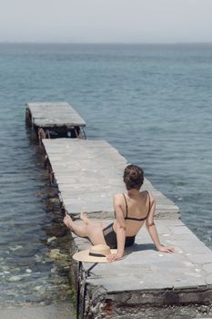 Woman relaxing on a pier by the ocean, enjoying a peaceful summer day.