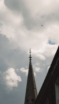 Dramatic view of a church steeple reaching into a cloudy sky, capturing a sense of spirituality and architecture.