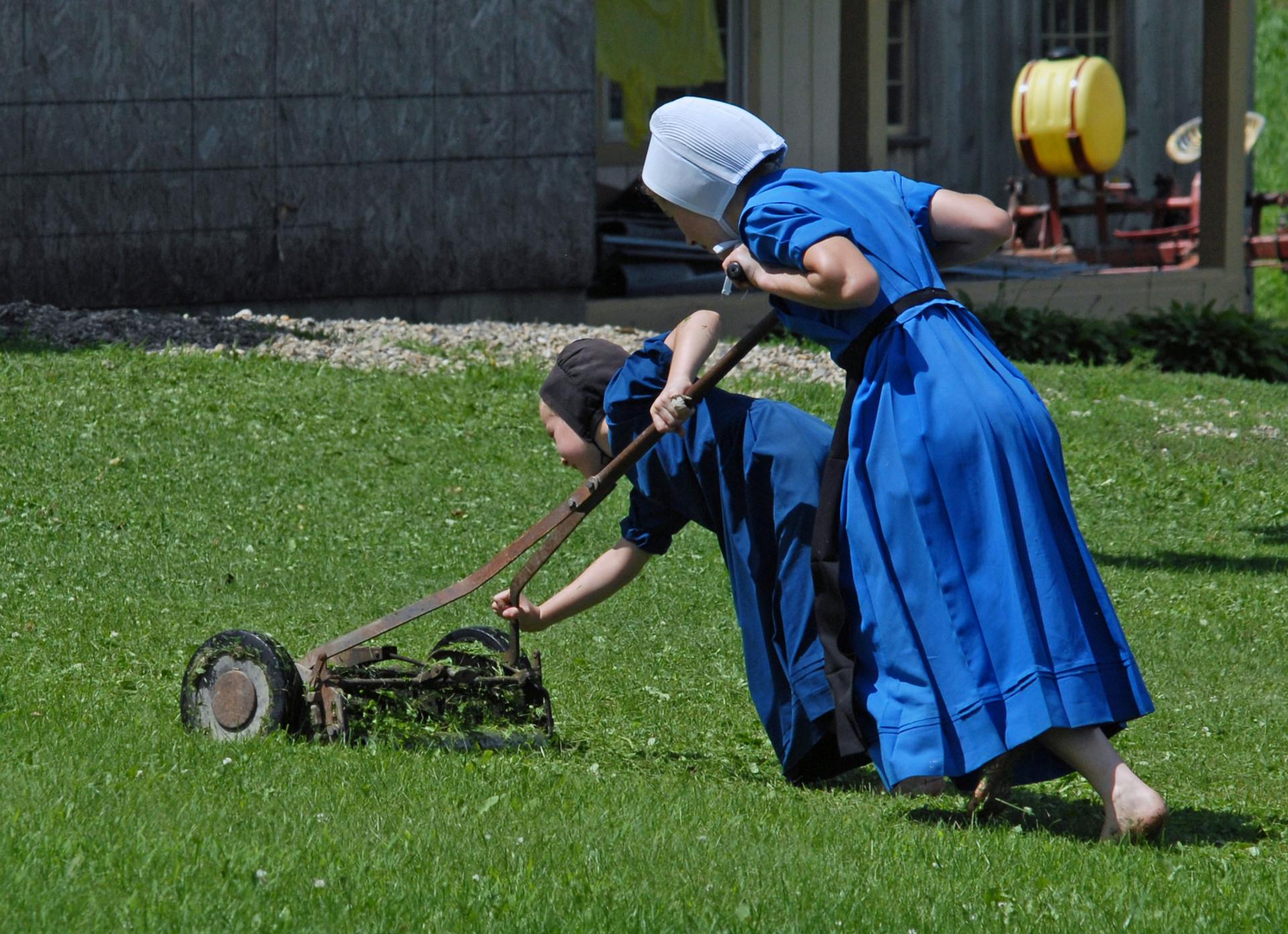 Teamwork/ Amish girls with mower