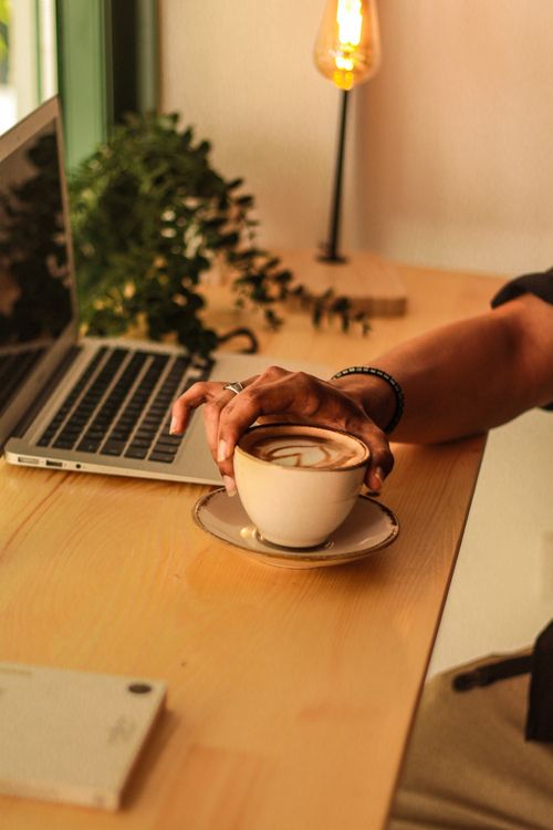 Free Warm and cozy indoor setting featuring a cup of coffee beside a laptop on a wooden desk. Stock Photo