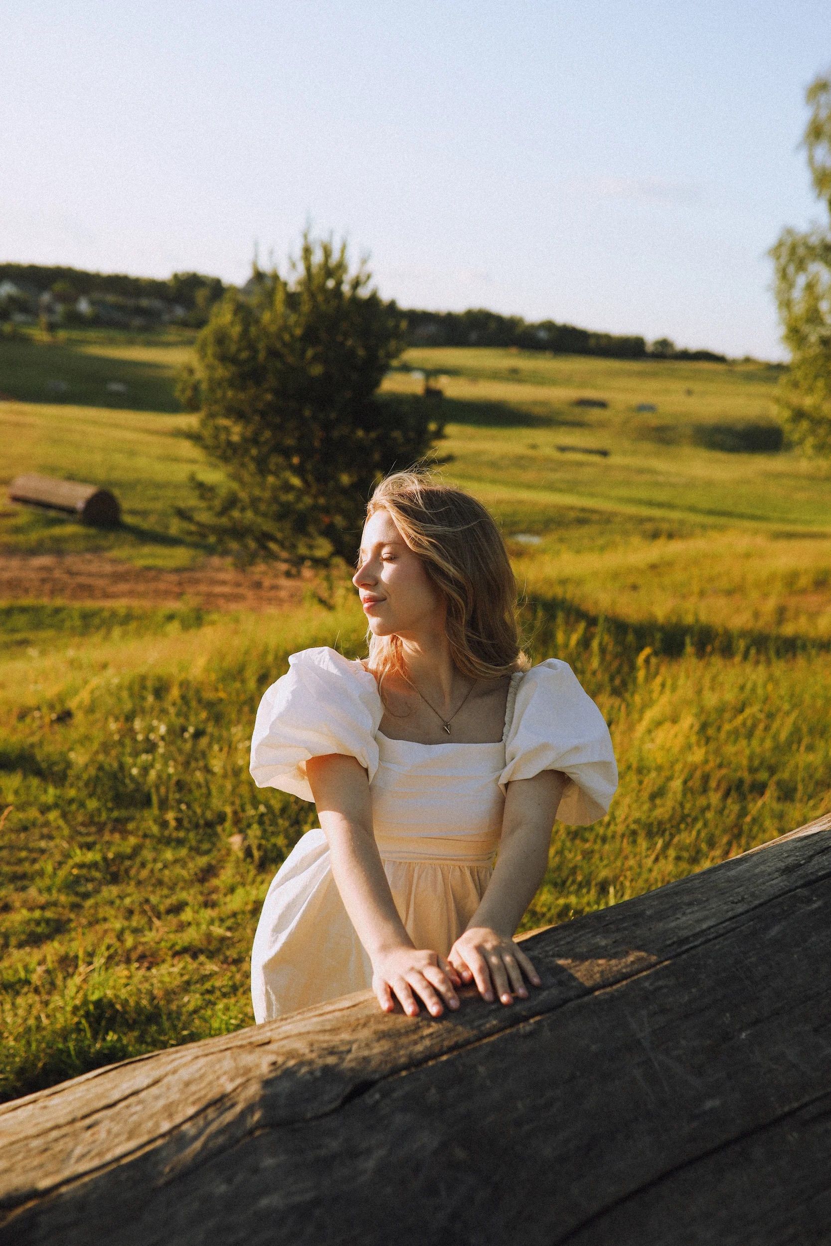 A woman in a white dress is leaning on a log · Free Stock Photo