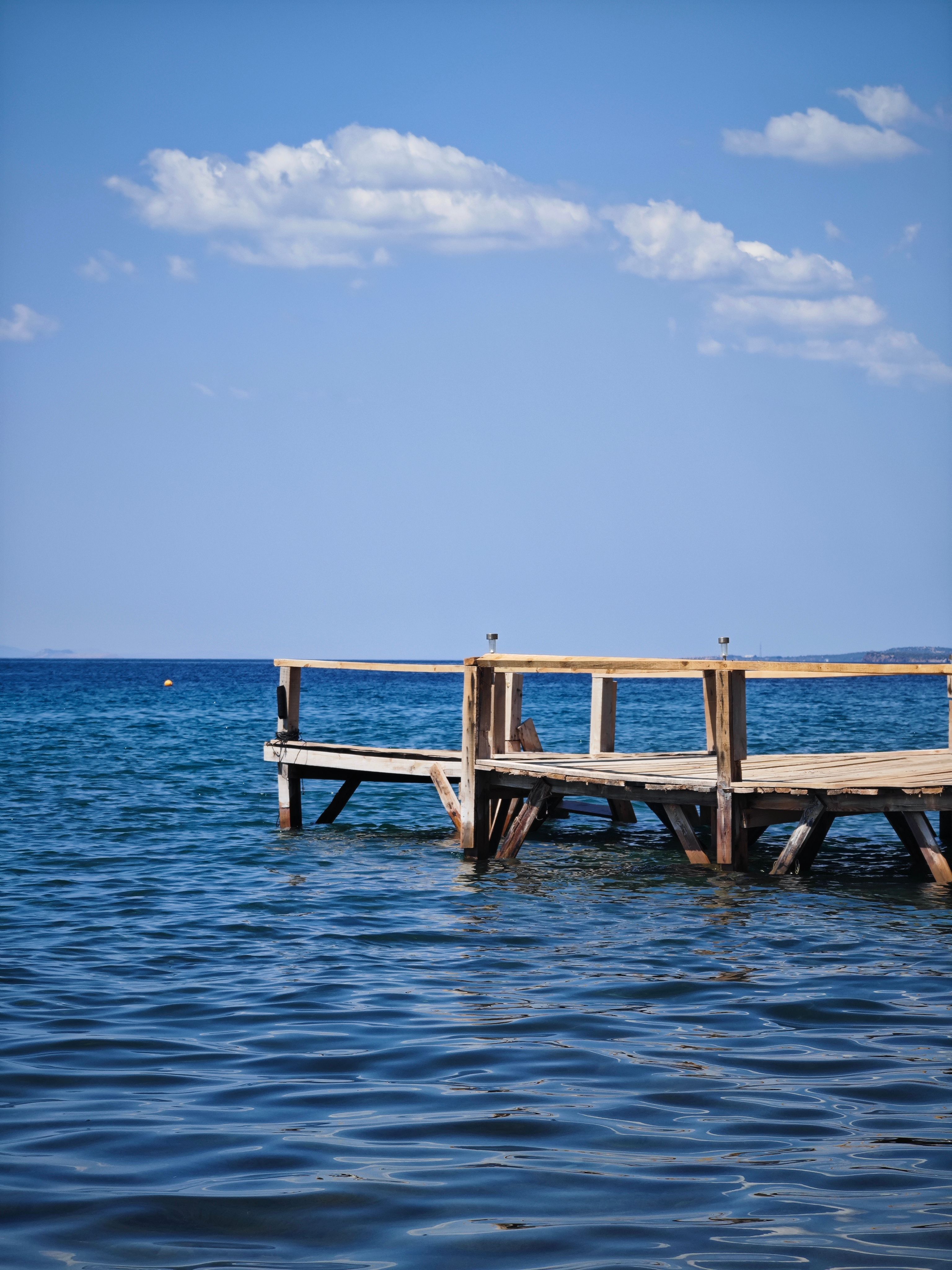 A wooden pier in the ocean with a blue sky · Free Stock Photo