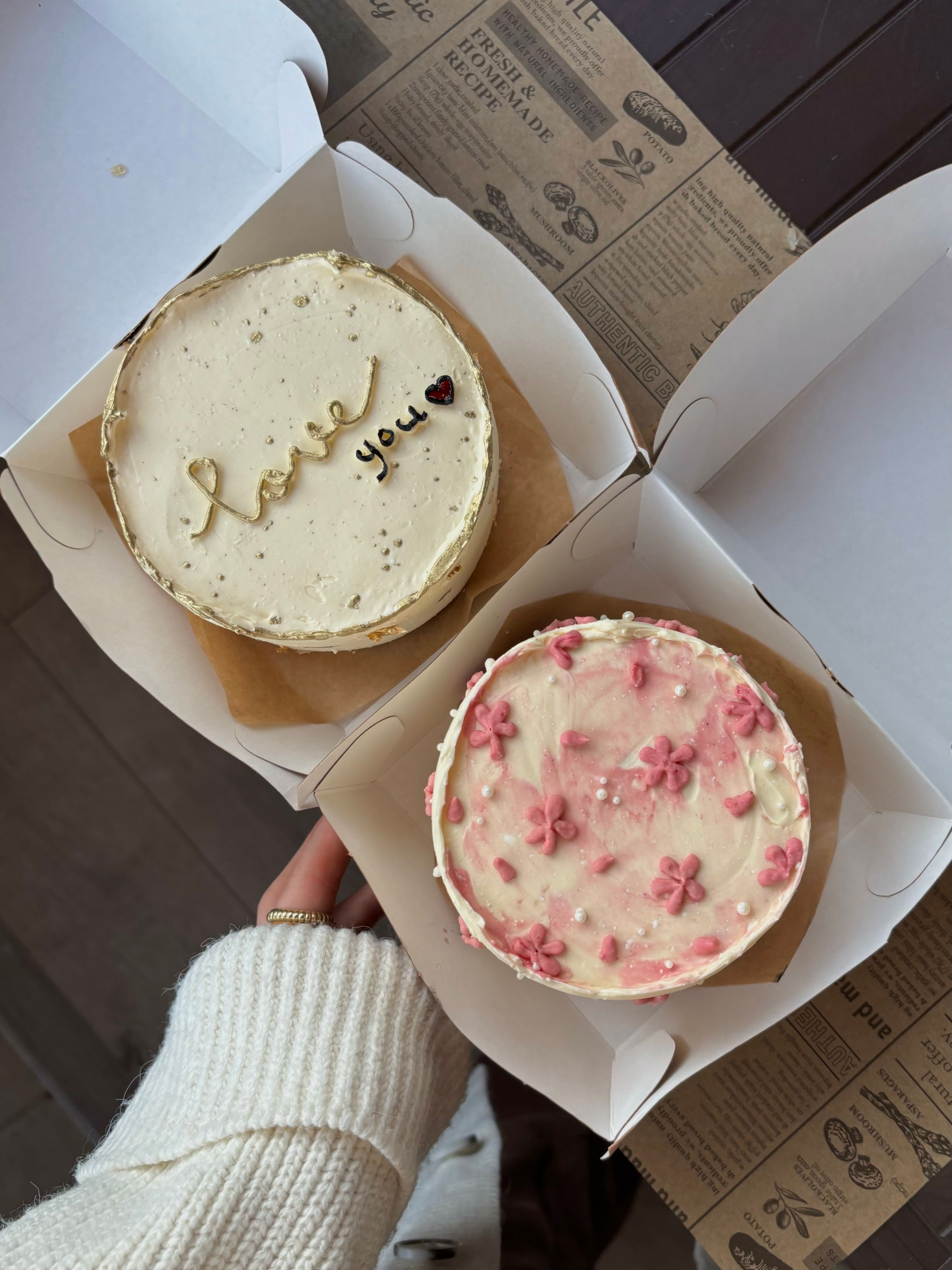 Two cakes in boxes with pink and white icing · Free Stock Photo