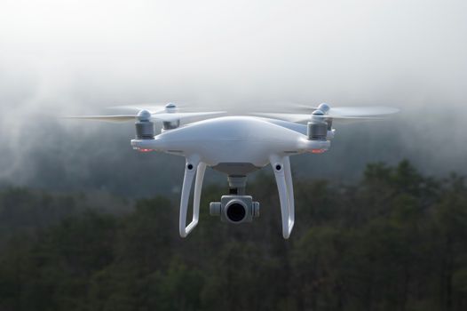 Drone hovering in a misty forest, capturing scenic aerial views.
