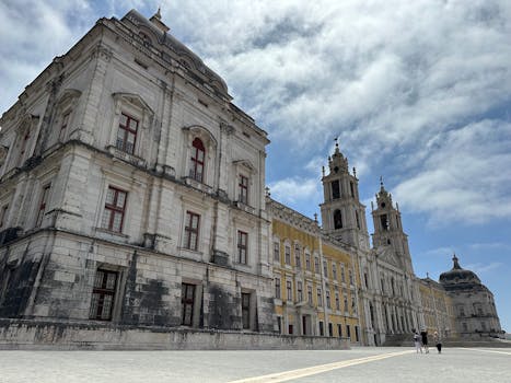 View of the historic Mafra National Palace's intricate facade under a vibrant sky.