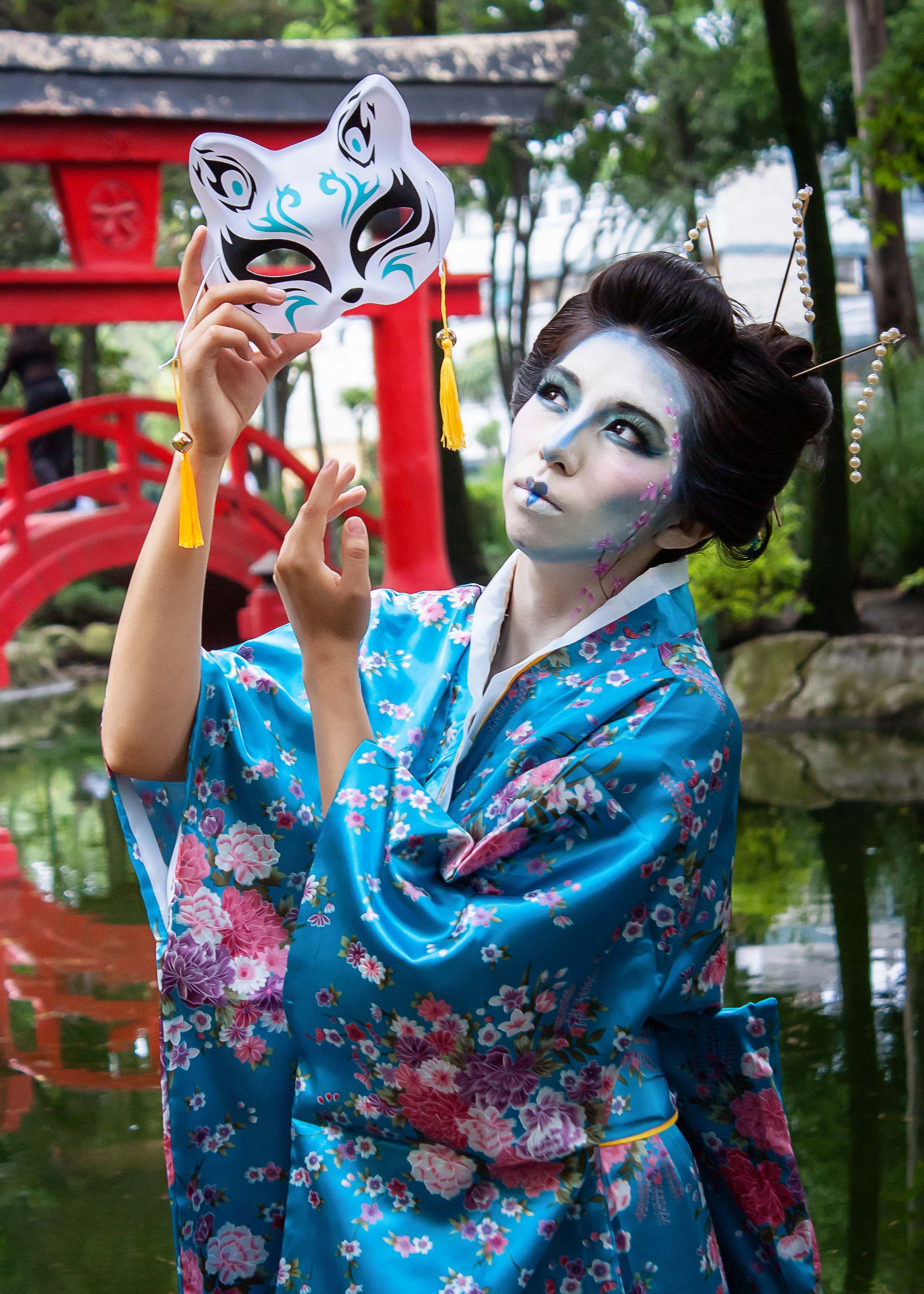 A woman in a geisha costume holding a mask · Free Stock Photo