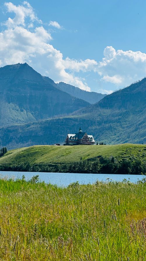 Free A serene mountain landscape features a lodge by a calm lake, under a clear blue sky. Stock Photo