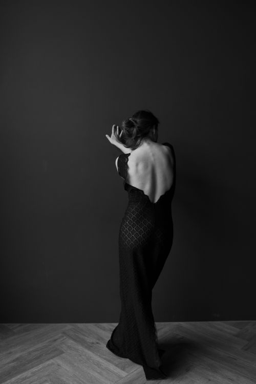 Free A sophisticated portrait of a woman in a black dress posing with elegance in a black and white setting. Stock Photo