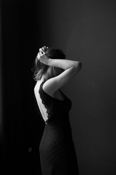 Graceful woman in a black dress captured in minimalist black and white photography.