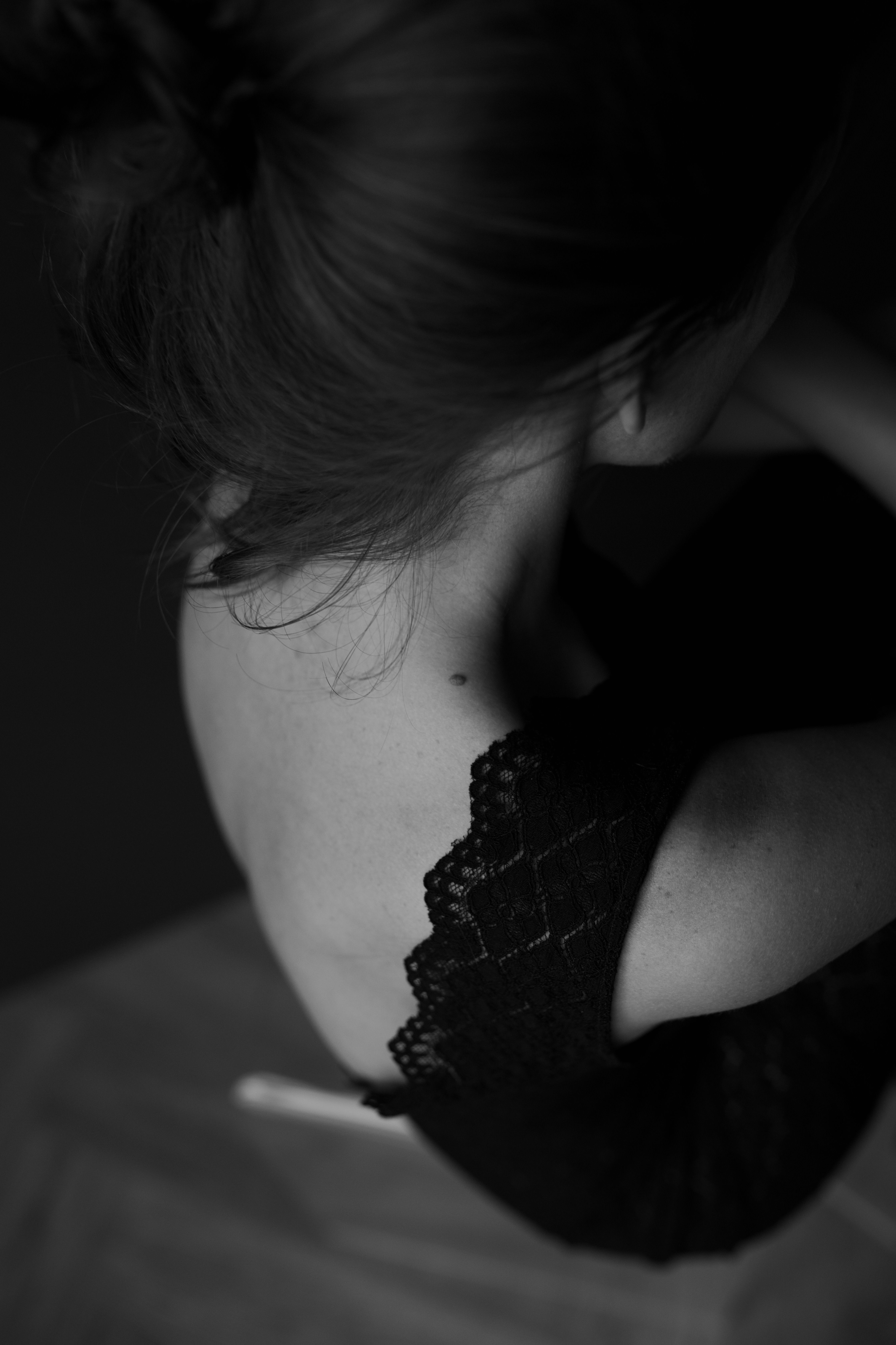 Dramatic black and white portrait showcasing a woman's elegant shoulder and hair from above.