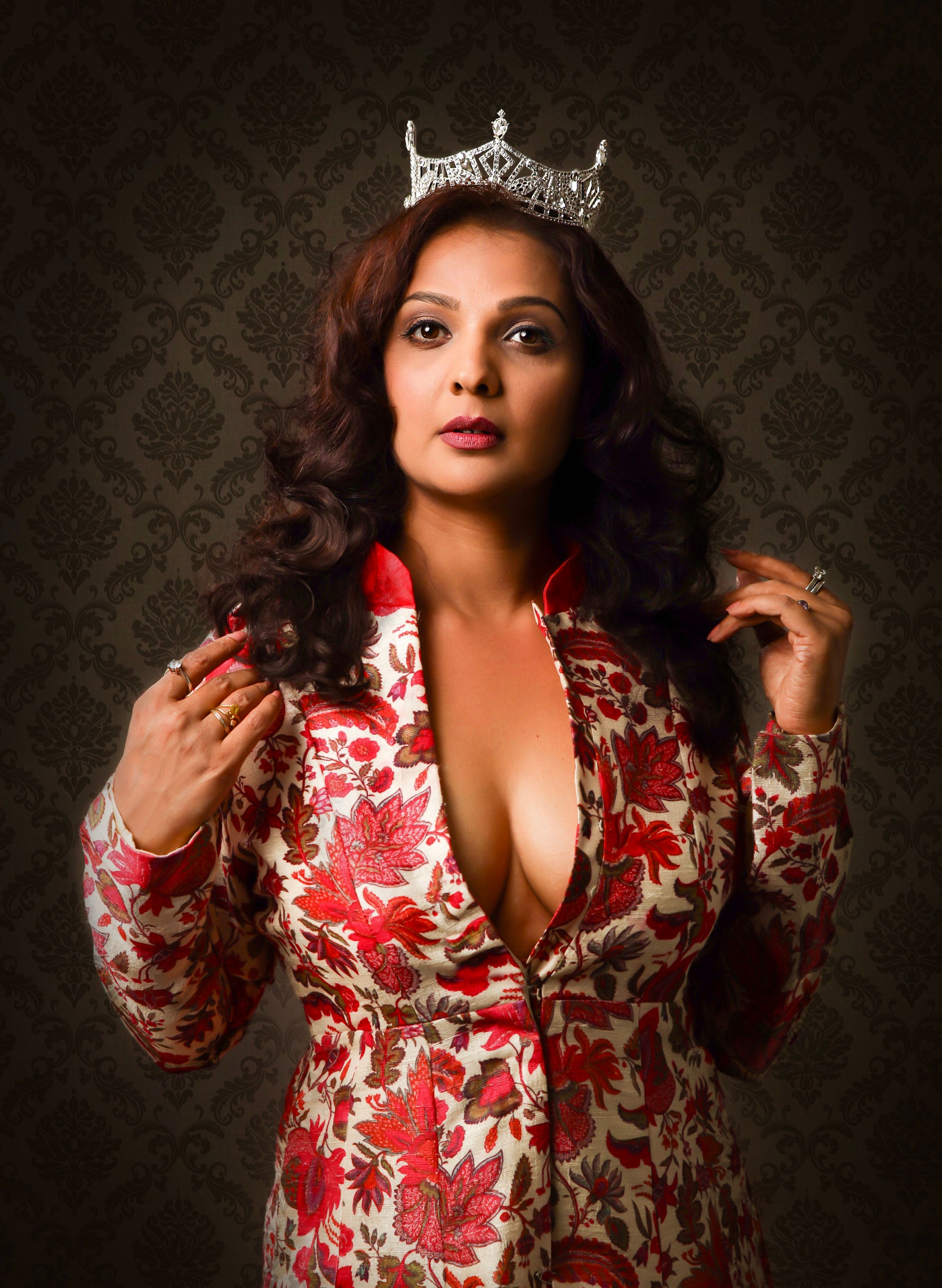 Glamorous portrait of a woman wearing a floral dress and tiara, exuding confidence and elegance.
