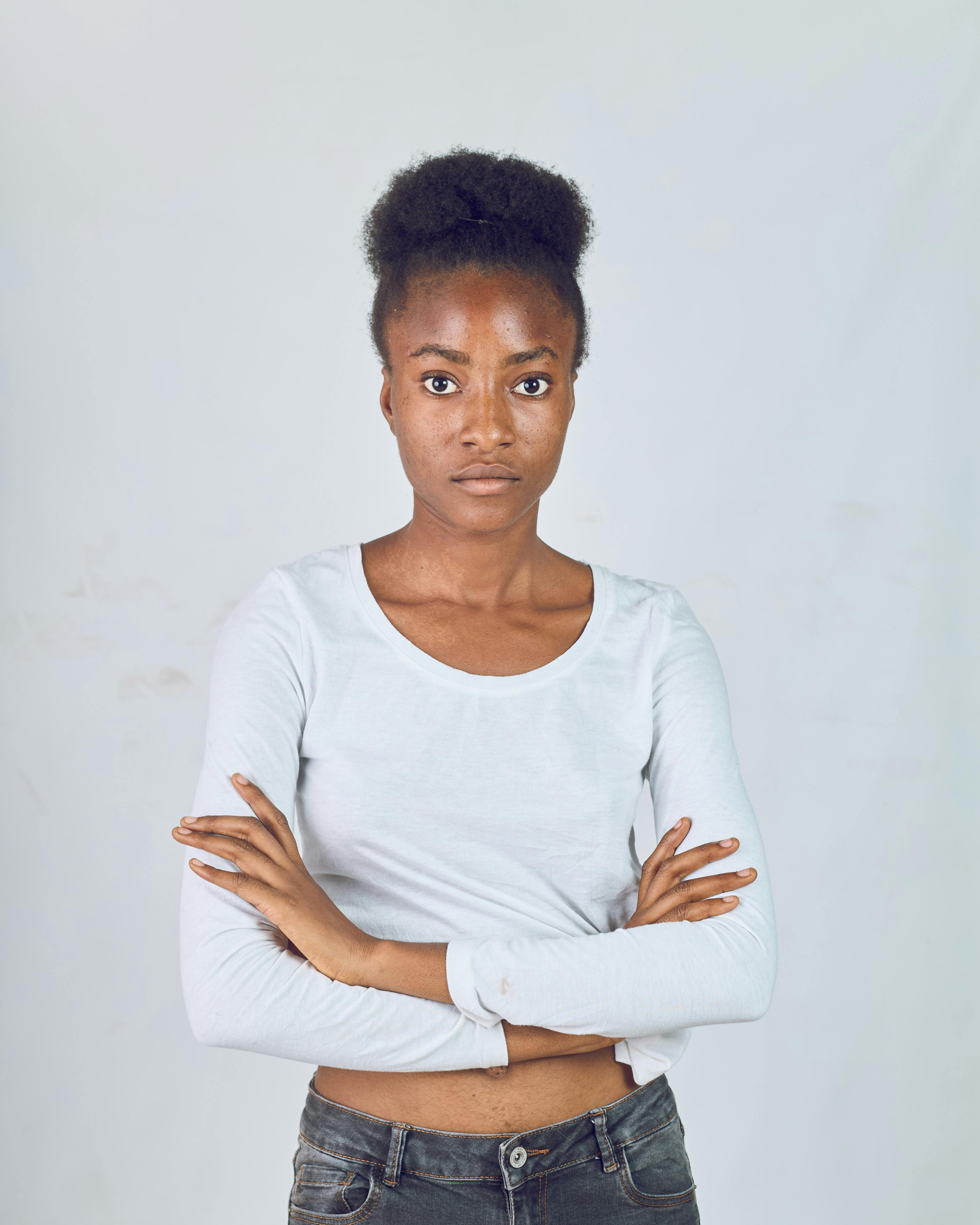 Portrait of a confident young woman standing indoors wearing a casual white top.