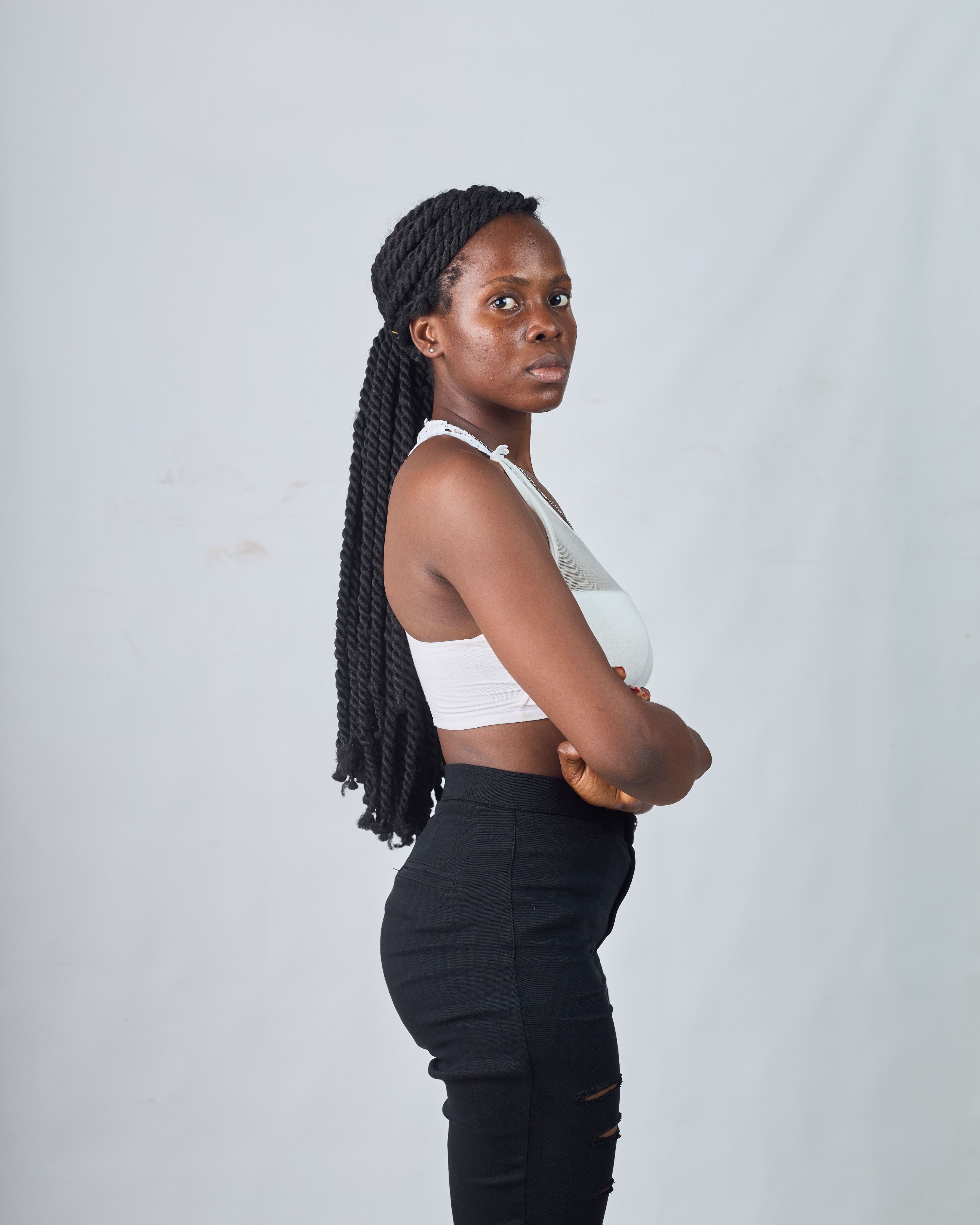 Elegantly posed young African woman in casual fashion against neutral backdrop.