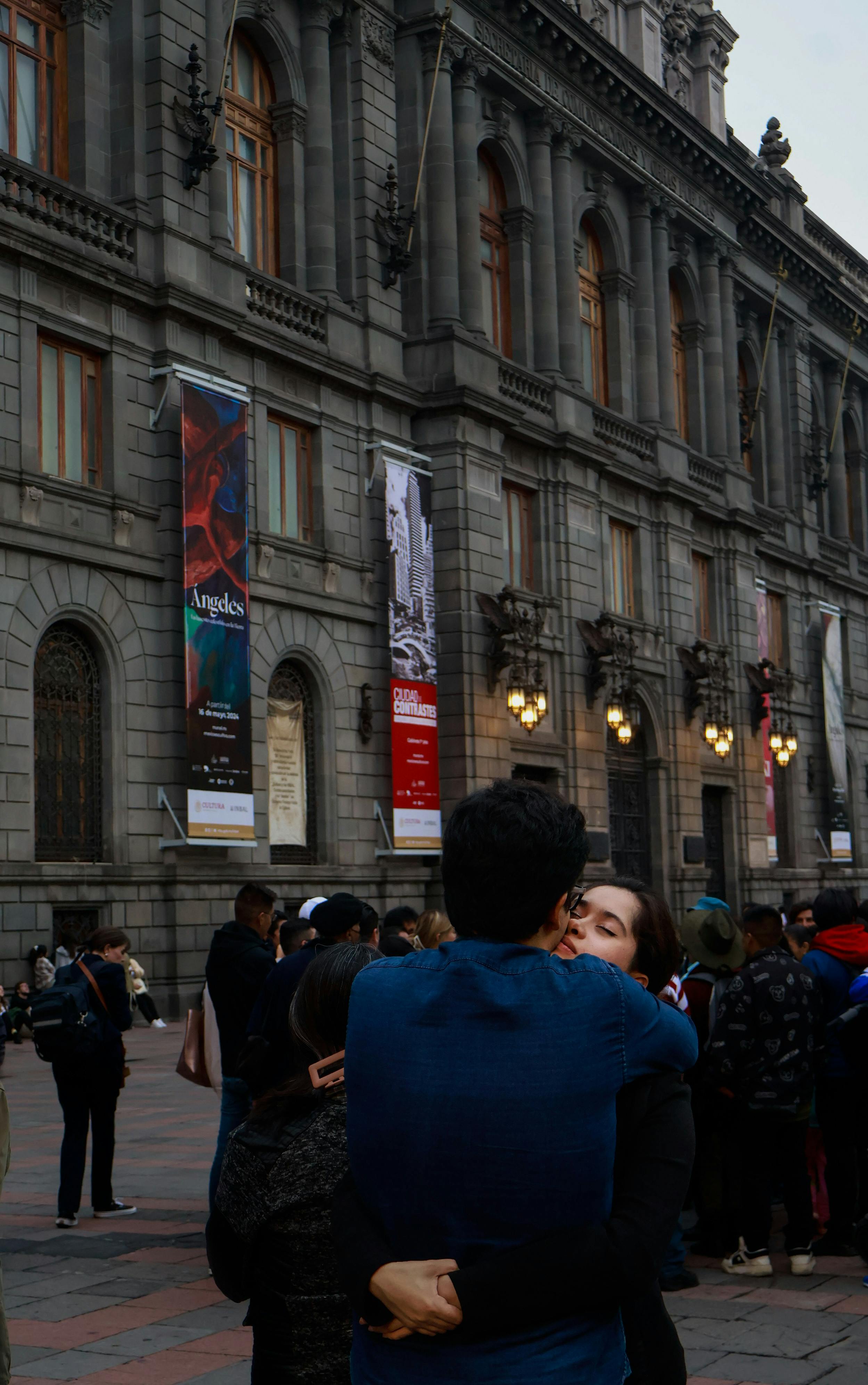 a couple hugging in front of a large building