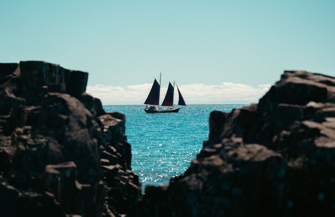 a sailboat glides on turquoise waters framed by rocky cliffs under a c