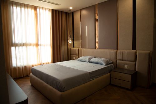 Free Luxurious bedroom featuring a stylish bed, soft curtains, and modern decor. Stock Photo
