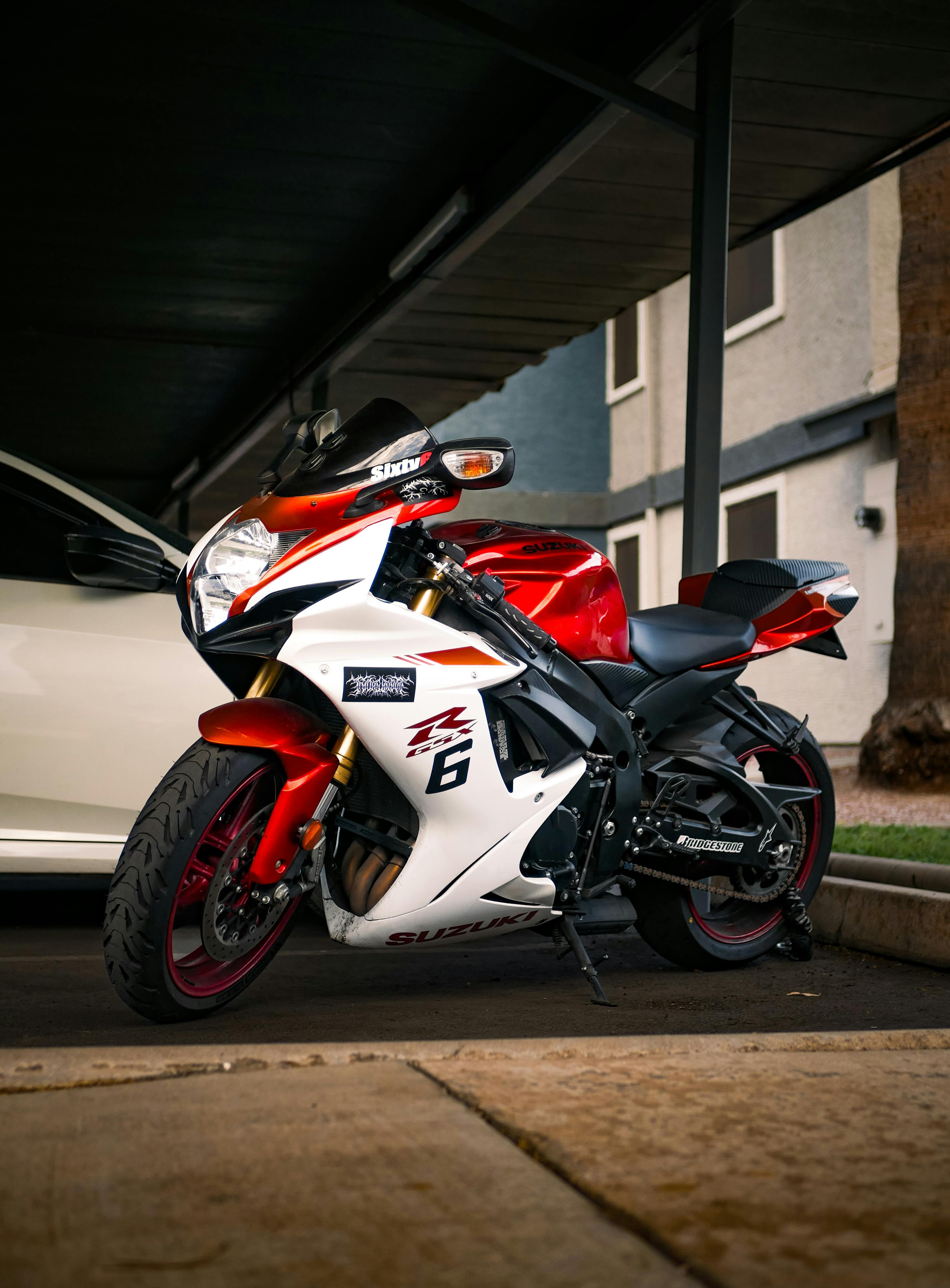 a red and white motorcycle parked under a car