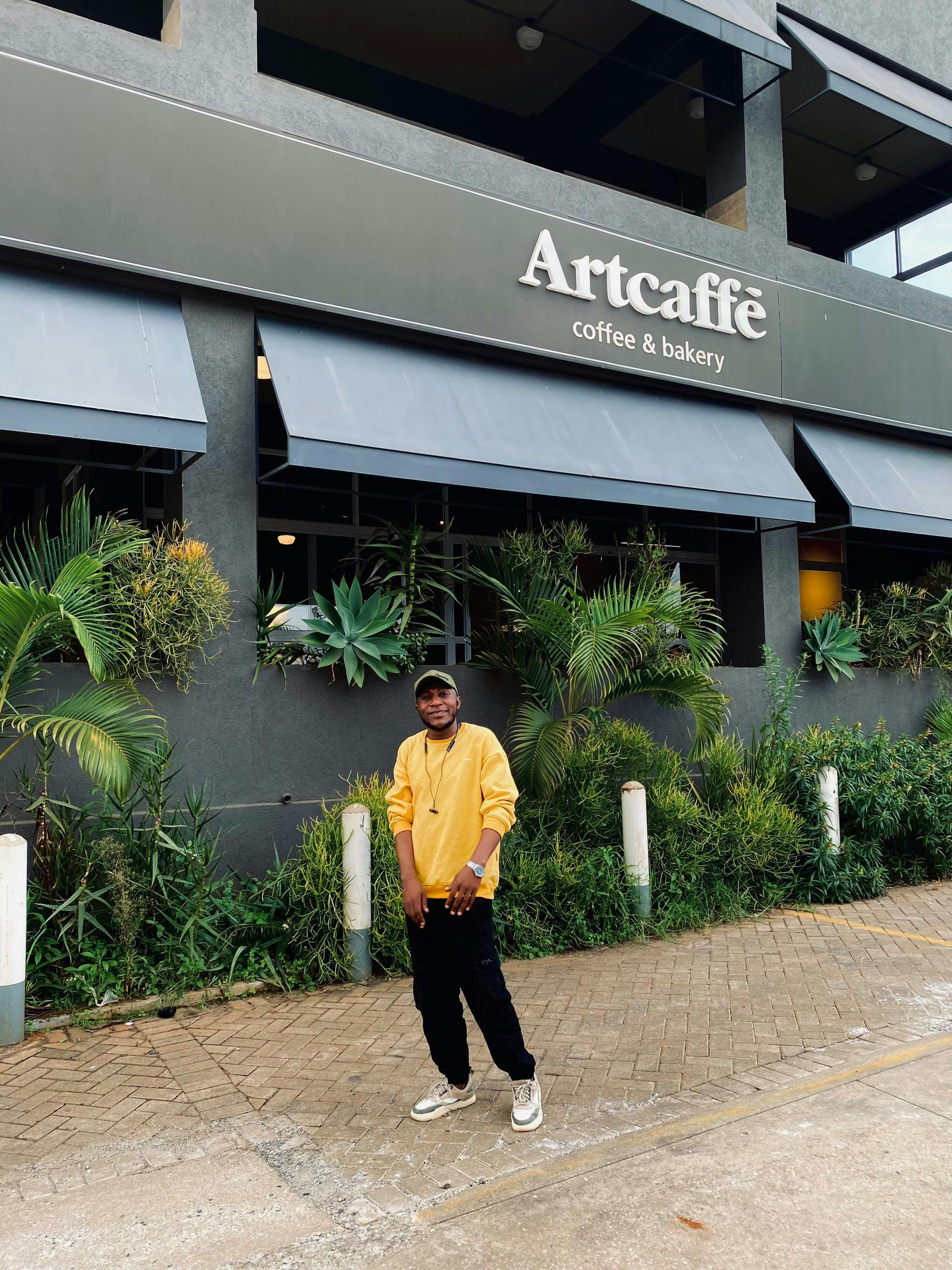 Young man standing outside Artcaffé in Nairobi, Kenya showcasing urban lifestyle.