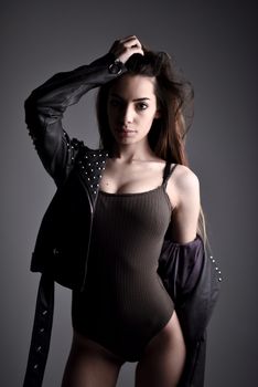 Portrait of a young woman in edgy fashion, featuring a studded jacket and ribbed bodysuit.