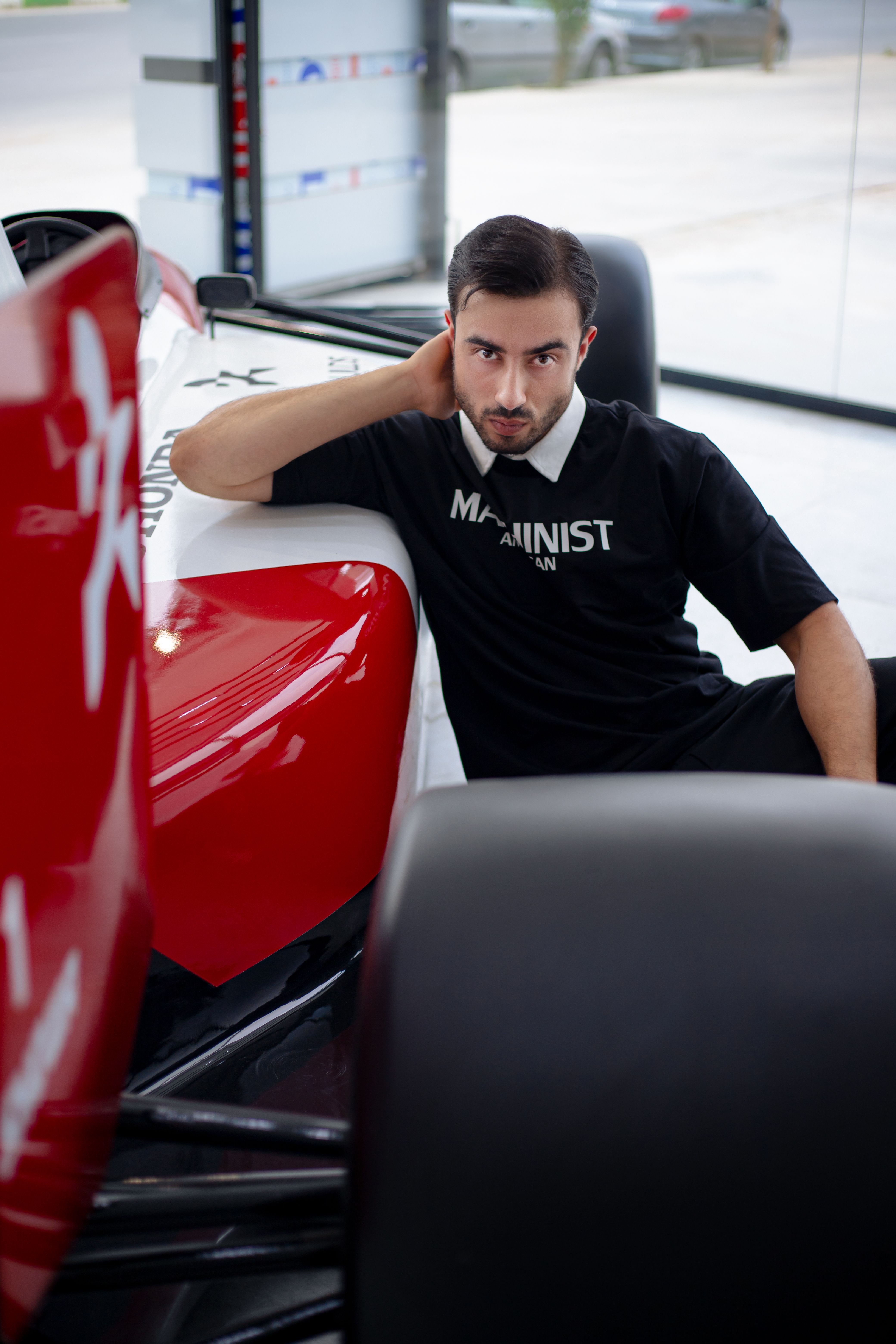A man sitting on the side of a red racing car · Free Stock Photo