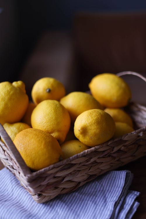 Free Close-up of bright yellow lemons in a wicker basket on a wooden table, perfect for culinary or health concepts. Stock Photo
