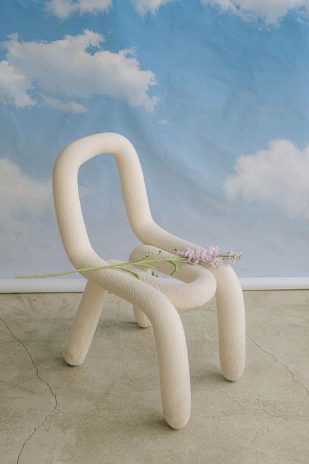 A minimalist abstract chair with a flower and cloud backdrop for artistic interior design.