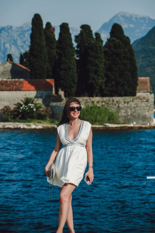 Free Woman in white dress and sunglasses enjoying the sea view on a sunny summer day. Stock Photo