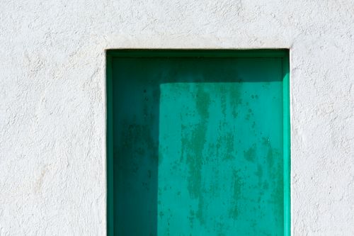 Free A rustic green door set in worn stucco, capturing vintage charm and muted textures. Stock Photo