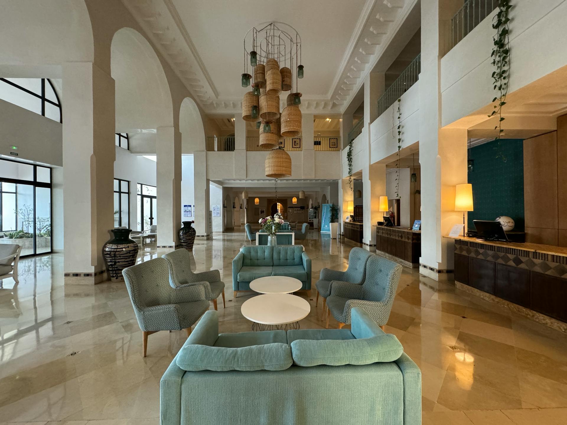 The lobby of a hotel with blue couches and a chandelier