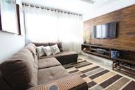 这间现代时尚的客厅配有棕色沙发、壁挂电视和室内装饰