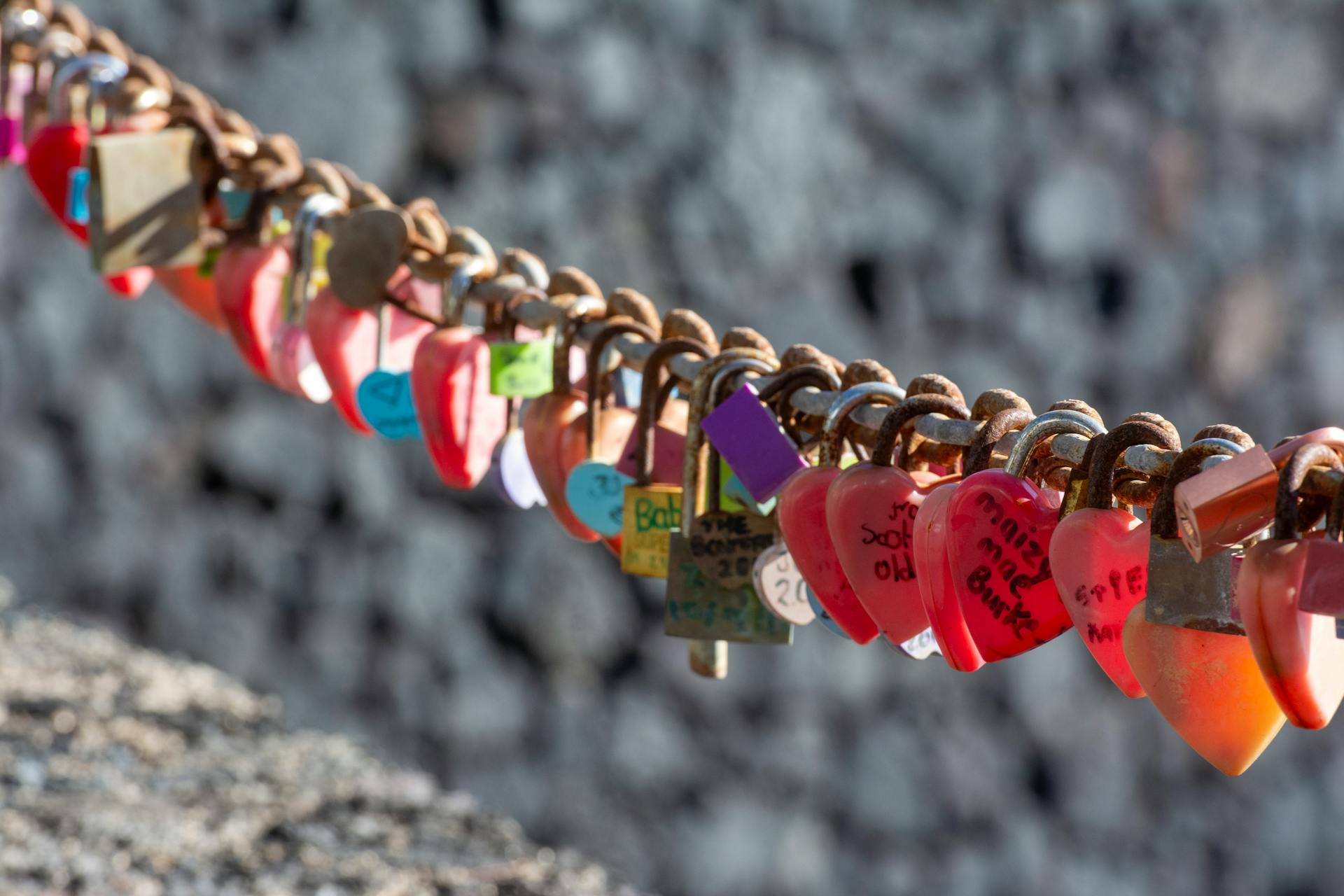 A bunch of heart shaped locks hanging from a chain