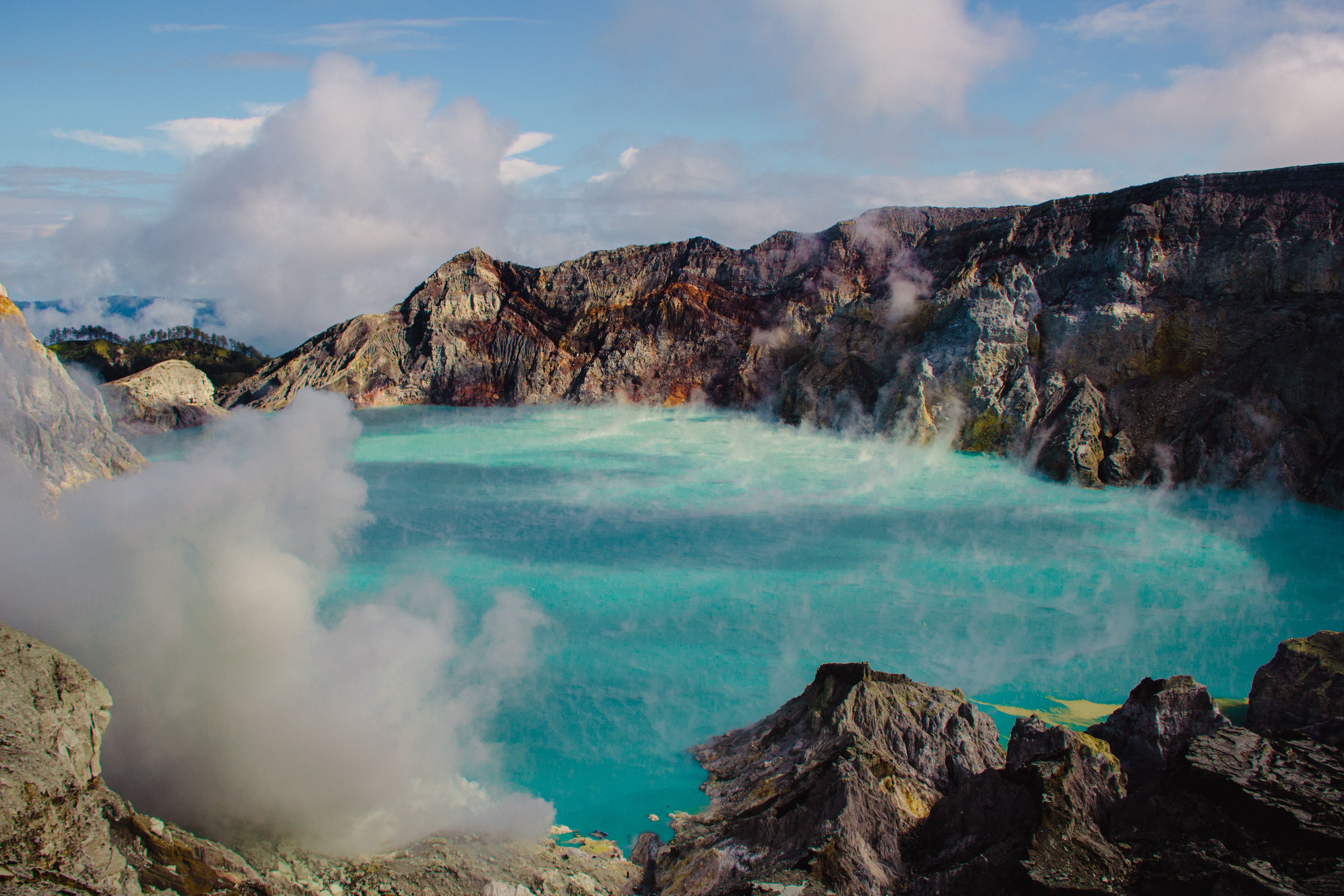 Pemandangan menakjubkan dari danau asam biru kehijauan Kawah Ijen yang dikelilingi oleh lanskap vulkanik yang terjal.