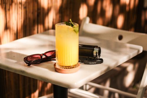 Free Lemonade with mint and lime on a sunlit table, surrounded by sunglasses and a camera. Stock Photo